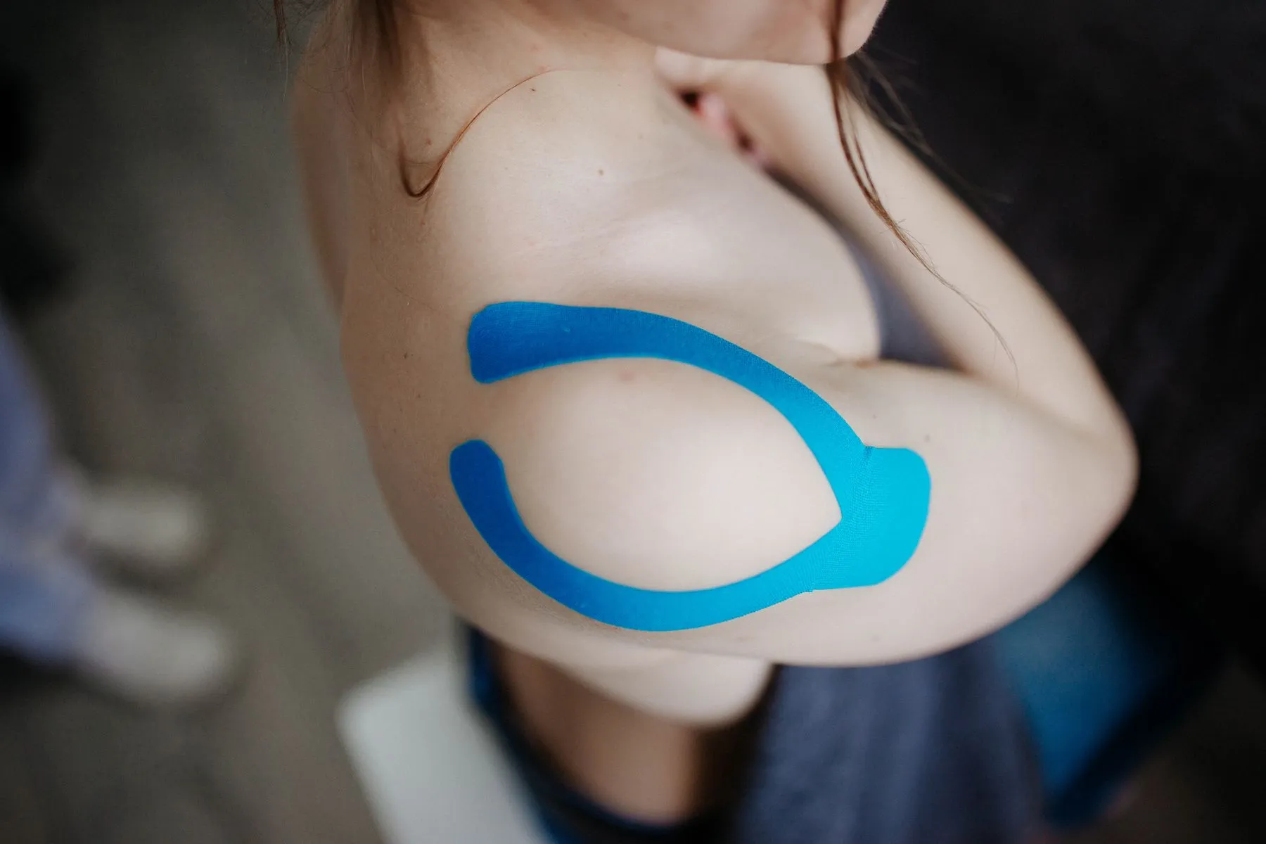 Blaues Kinesio-Tape klebt auf einer Schulter – Symbolbild für das Kinesio-Taping